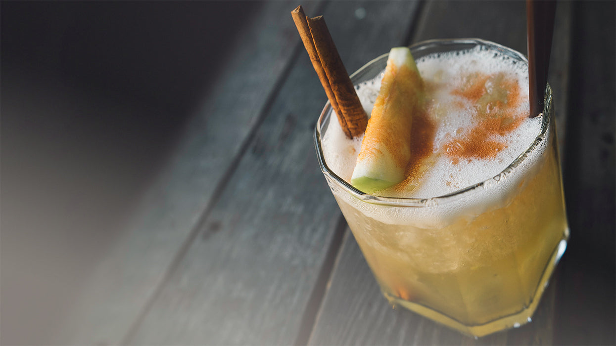 Apfel Zimt Kombucha im Glas Zimtstange Apfelscheibe Holztisch